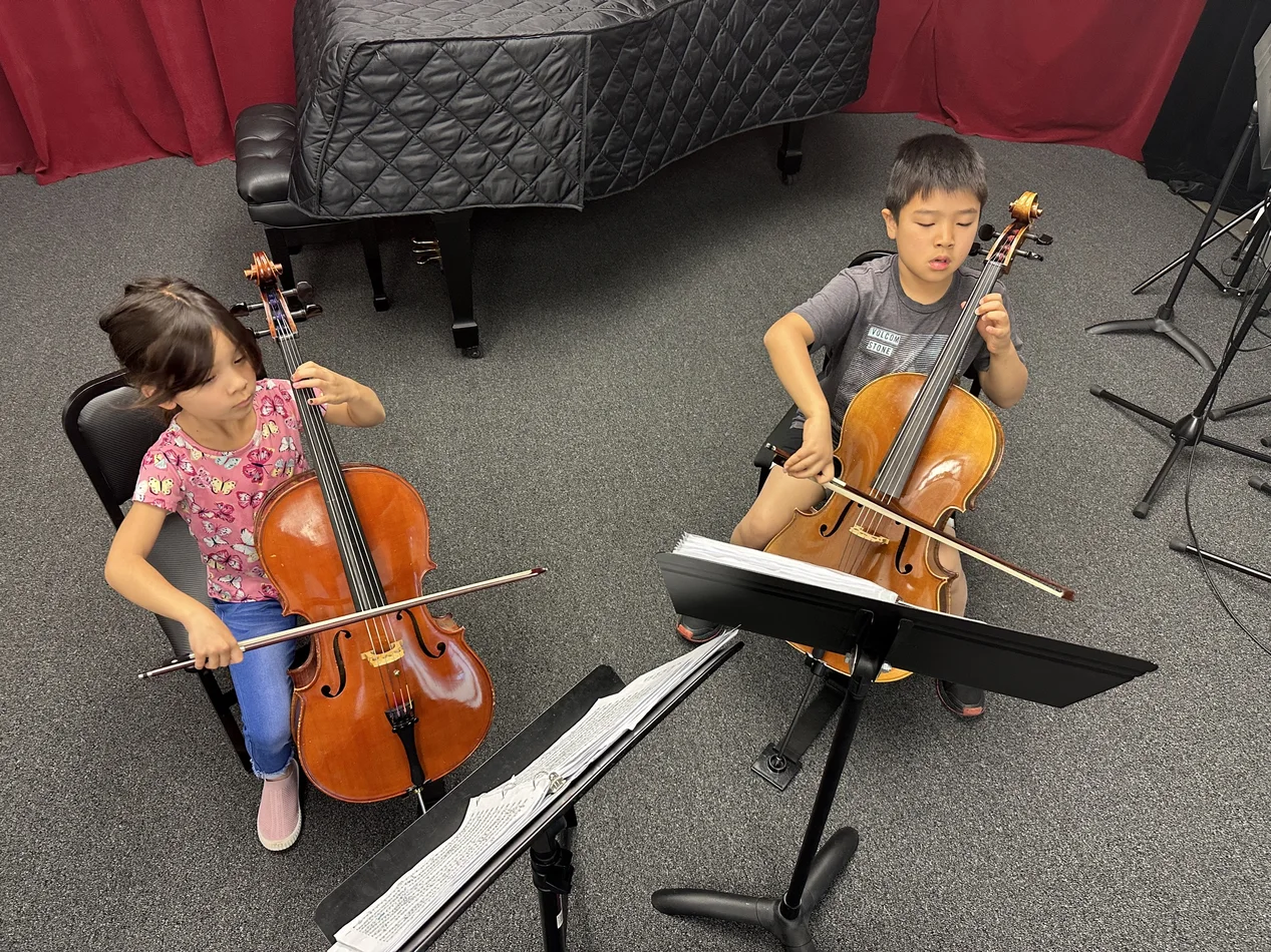 Young cello students rehearsing together with music stands