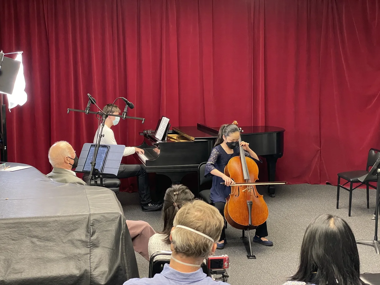 Cello student performing in a studio class with pianist and audience